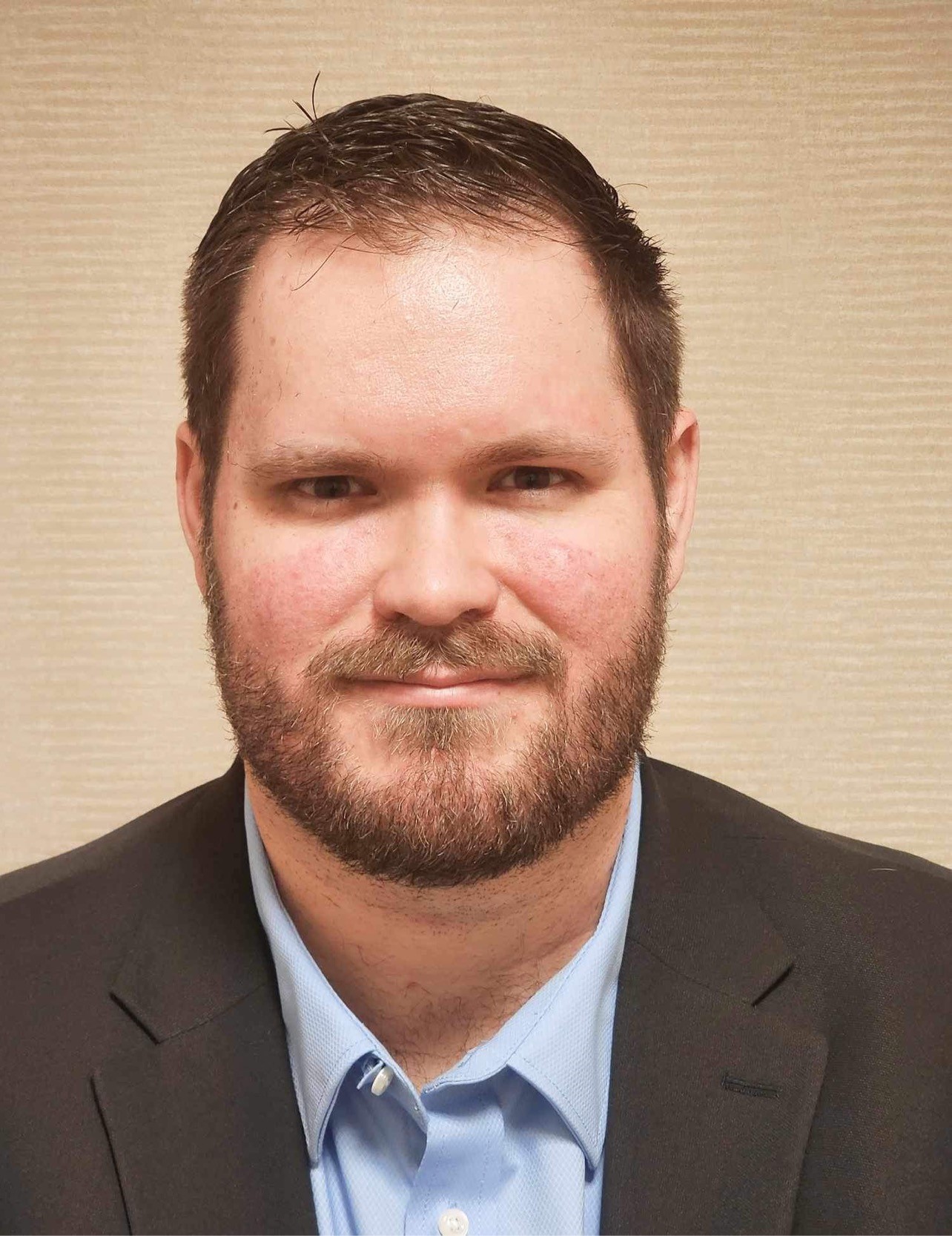 Photo of a man in a suit with a slight smile